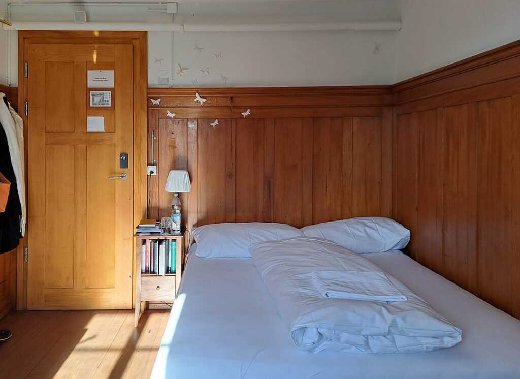 Artist-in-Residence-Raum mit Bett, Nachtschrank und Schmetterlingsfaltungen