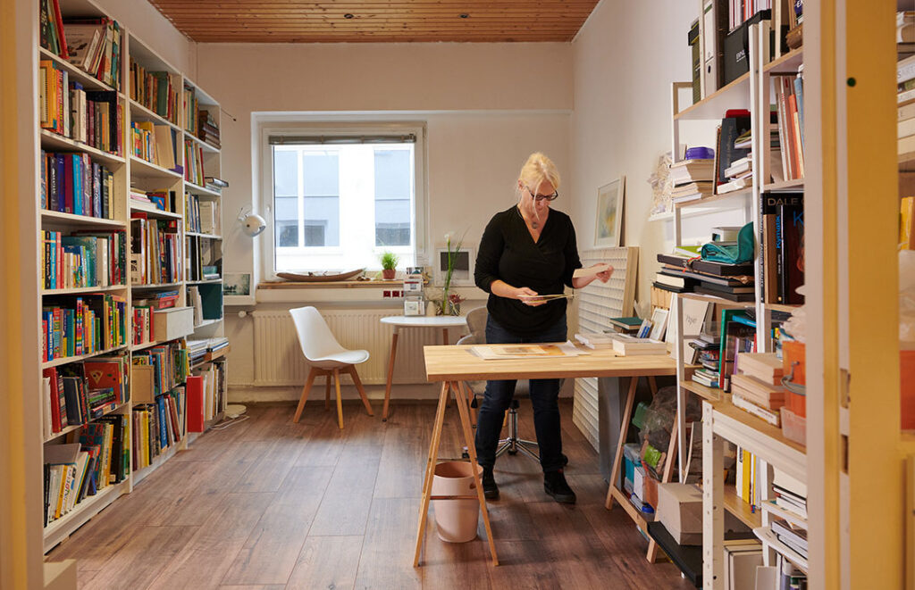 Frau in einem Raum mit Büchern stellt Unterlagen für eine Bewerbung zusammen