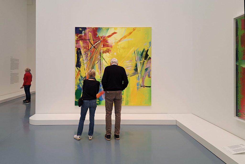 Kunst bewerten: Menschen in einem Museum vor einem abstrakten Gemälde von Gerhard Richter. 